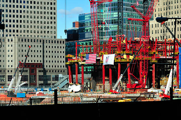 New York, NY, USA - August 3, 2011: Union workers direct traffic on Church Street in Downtown Manhattan outside the World Trade Center Ground Zero construction sight so that concrete can be delivered to the site.  The cranes in the foreground are in the area of the National September 11 Memorial Plaza.  In the center is One World Trade Center with two cranes on top.  Seven World Trade Center, to the right, has been completed. The construction site is surrounded by a security fence which is decorated with depictions of the completed buildings and Plaza.