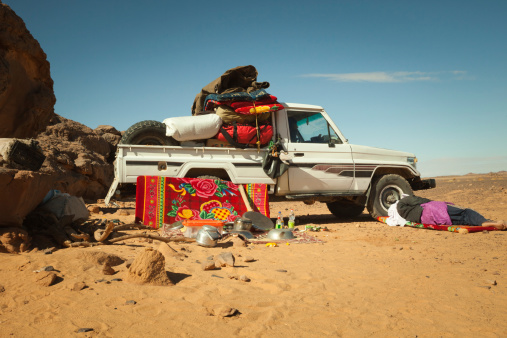 Sahara, Libya - December 27, 2010: Libyan man resting at noon next to his fully loaded vehicle in the Sahara desert