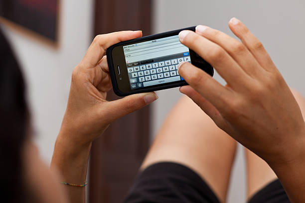 Milan, Italy - July 1, 2011: Close up of young woman's hands writing Message on Iphone 4. Iphone is a smart phone produced by Apple Computers.