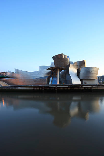 Guggenheim Museum Bilbao Bilbao, Spain - March 31, 2011: View of Guggenheim Museum Bilbao, designed by the architect Frank Gehry, reflected in Nervion River during dusk. It is a mayor tourist attraction in Bilbao and an architectural milestone of the last century. frank gehry building stock pictures, royalty-free photos & images