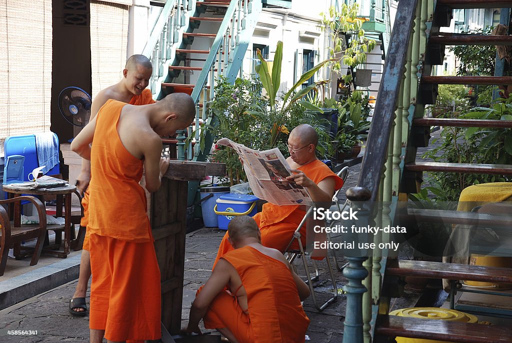 Daily monk life Bangkok, Thailand - December 14, 2008: 4 Buddhist monks spending time between residences next to Marble Temple. One of the monks reading a daily newspaper, other three busy with building a wooden bench. Bangkok Stock Photo