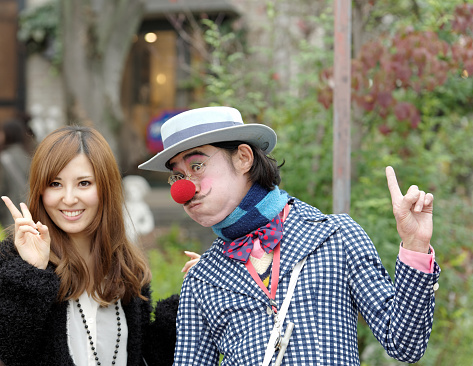 Arashiyama,Kyoto,Japan - November 13, 2010: Man dressed as a clown is entertaining tourists in the streets of Arashiyama, a touristic district outside Kyoto. Together with a  Japanese woman he is posing for a photographer. 