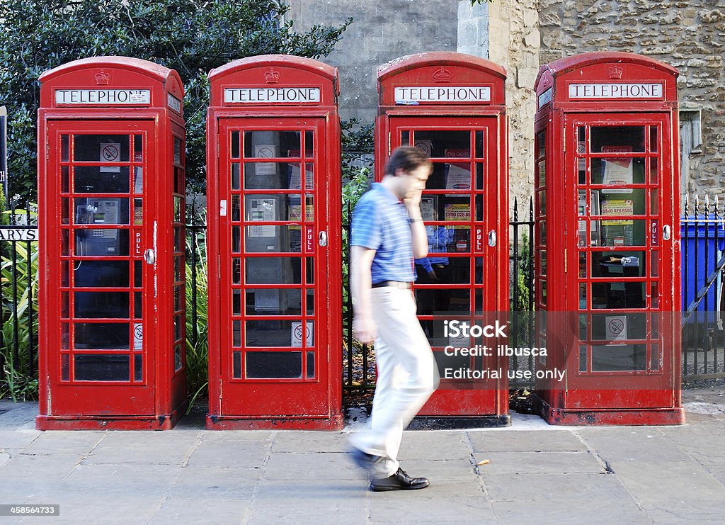 Uomo con cellulare a piedi davanti della cabina telefonica - Foto stock royalty-free di Adulto