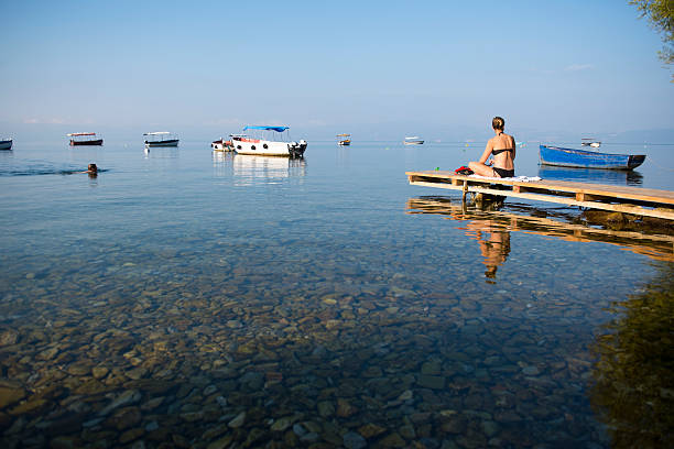 Ohrid, Macedonia - September 3, 2013: A Polish man (swimming) and woman (sunning after a swim) enjoy the early morning beauty on Lake Ohrid.