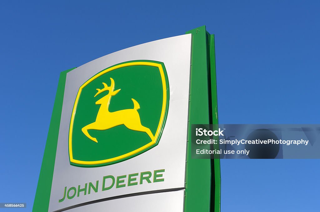 John Deere sign against blue sky Elmira, Ontario, Canada - March 25, 2011: A John Deere farm equipment sign. John Deere is an American corporation based in Moline, Illinois, and the leading manufacturer of agricultural machinery in the world. In 2010, it was listed as 107th in the Fortune 500 ranking. Deere and Company agricultural products, usually sold under the John Deere name, include tractors, combine harvesters, balers, planters/seeders, ATVs and forestry equipment. John Deere Stock Photo