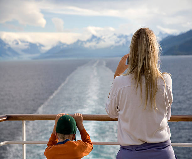 Mother and son looking over the railing of cruise ship stock photo