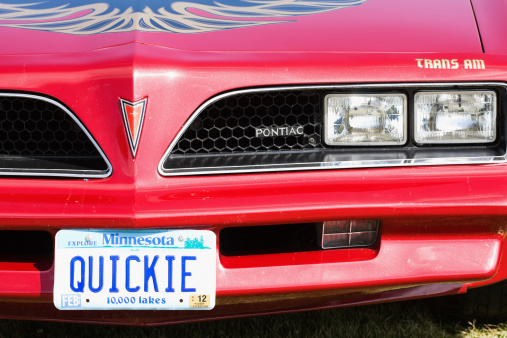 Fosston, USA - August 27, 2011:  The front of a red Pontiac Trans-Am with a personalized Minnesota license plate with letters spelling the word QUICKIE.  The car is on display at a classic car show.