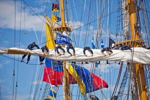 Greenock, Scotland, UK - 9th July, 2011: Seven young sailors stowing a sail onto a yard of the Colombian Tall Ship ARC Gloria after the first leg, from Waterford to Greenock, of the Tall Ships Race 2011. The ARC Gloria is a a training ship owned and operated by the Colombian government.