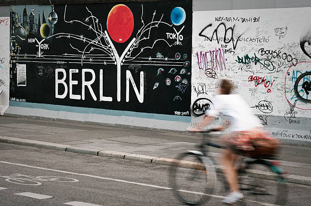 женщина, езда на велосипеде вдоль берлинская стена - berlin wall стоковые фото и изображения