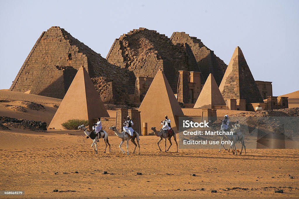 Meroe Pyramids in Sudan MEROE PYRAMIDS, SUDAN - NOV 02, 2007 : Unidentified Sudanese bedouins ride camels with the famous Meroe pyramids of the ancient Nubian city in the background, on November 02, 2007 in Sudan Sudan Stock Photo