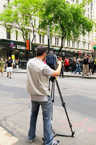 New York City, USA - May 21st 2011: Man filming people in front of Trinity Church, 79 Broadway Lower Manhattan, New York City