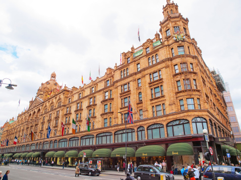 London, United Kingdom - May 21, 2009 : Front view of Harrods Building and the street full of people and black taxi cars