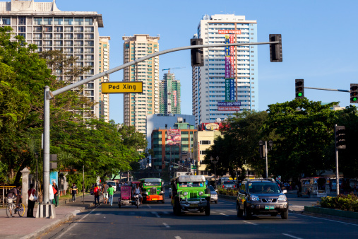 Manila, Philippines - April 19, 2012:Colourful Jeepney vehicles stopped at some lights in Metro Manila. People can be seen walking on the footpath.