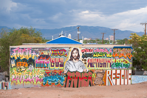 Albuquerque, New Mexico, USA - July 30, 2011: Huge mural on commercial building on Central Avenue (Route 66) depicting religious motifs and icons including large scale text: Holy God, Almighty, God, Rescue, Love, Father, all illustrated in a comic book and graffiti style. The central and dominant feature is a torso of Jesus Christ.