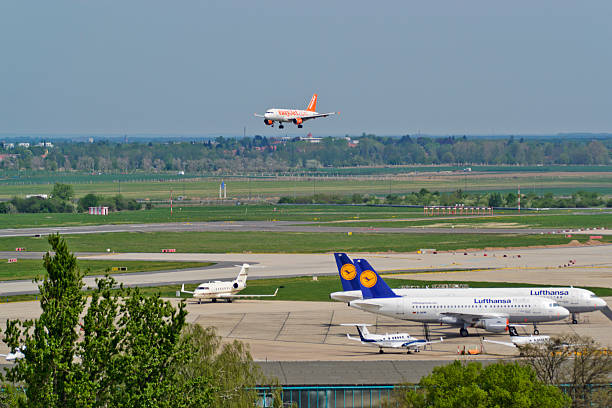 Schoenefeld, Germany - April 30, 2012: An Airbus A319-111 by easyJet in landing approach at the airport Berlin-Schönefeld. easyJet is a great British low cost airline. The Airbus A319 in the easyJet version can carry up to 156 passengers. The airport Berlin-Schönefeld is currently under development for the new Airport Berlin Brandenburg International. In the foreground, including two aircraft of the airline, Lufthansa, an Airbus A319-100 and A321-200.