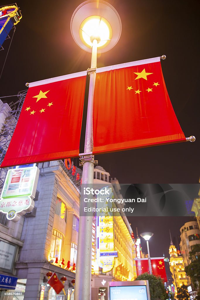 Chinese Flags and Colorful Neon Signs on Nanjing Road Shanghai, China - Oct 1, 2013: Chinese flags fluttering and colourful neon signs and street lights glowing in the vibrant dusk of Nanjing Road, Shanghai's most famous shopping street on which there are numerous stores. Architecture Stock Photo