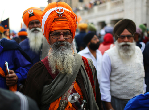 New Delhi, India - November 23, 2012: Indian Sikh devotees march during a festival in Old Delhi to celebrate the birhday of one of the founders of Sikhism. The Sikh religion was founded by Guru Nanak. The origins of Sikhism lie in the teachings of Guru Nanak and his successors. The essence of Sikh teaching is summed up by Nanak in these words: \
