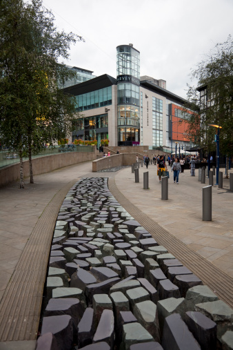 Manchester, UK - August 20, 2011: A footpath in Exchange Square leads towards the Harvey Nichols department store. Many pedestrians can be seen.