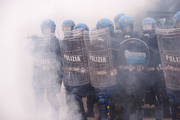 Police in tear gas Padua, Italy - may 13, 2009. An Anti-riot squad of Italian Police during an hard training in a Police structure. The cloud is a true tear gas cloud. tear gas stock pictures, royalty-free photos & images