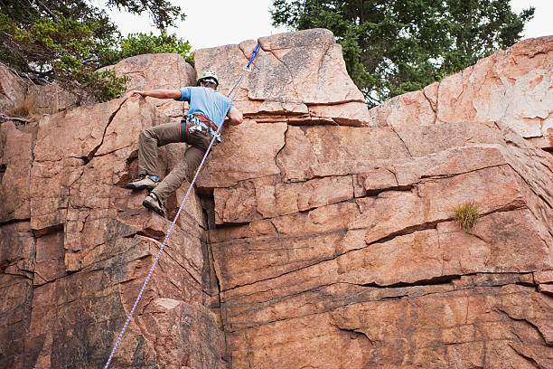 Acadia National Park, Maine, USA - August 23, 2010:A rock climbing guide from Bar Harbor, Maine, leads the way up Otter Cliff in Acadia National Park.