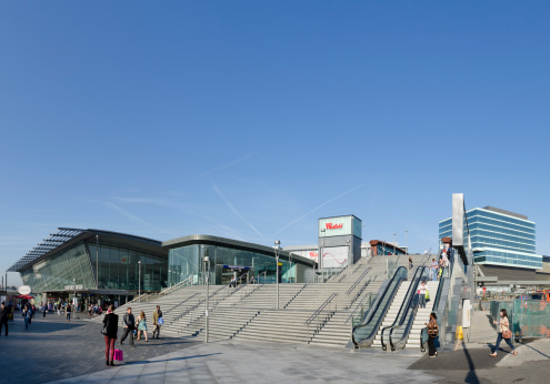 London, United Kingdom - October 1, 2011: Steps and escalators lead up towards the entrance of Westfield Stratford City, a shopping centre adjacent to the London Olympic site. The building on the left is Stratford Station, a busy railway station that services several different lines. Westfield shopping centre is one of the largest urban shopping malls in Europe and part of a redevelopment plan for the area surrounding the London Olympic Games site. Westfield are a Australian shopping centre group.