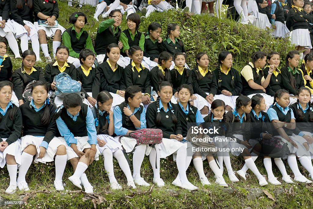 Schoolgirls in Sikkim Watching Soccer Pelling, Sikkim, India - May 26th, 2012: Girls in school uniforms sitting on grass terraces and watching soccer game(not seen), near village school in Pelling. Education Stock Photo