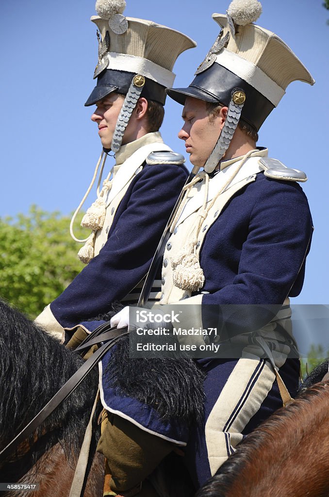 Lancers Warsaw, Poland - May 3rd, 2012: Two lancers in historical costumes from XIX century, sitting on maroon horsebacks, over a blue sky. Adult Stock Photo