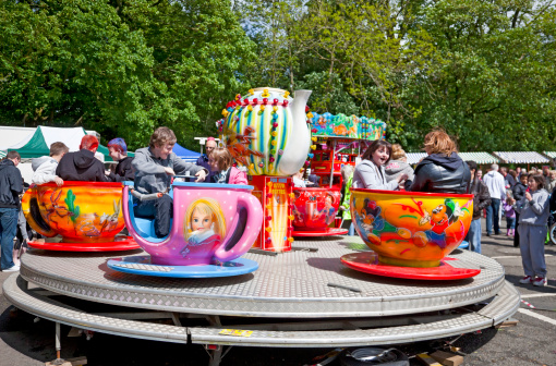Mauchline, Scotland, UK - 28th May, 2011: Teenagers and children in a Teacups fairground ride at the Mauchline Holy Fair in East Ayrshire.