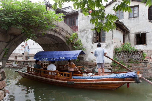 Zhouzhuang, China - July, 15th 2007 : Villagers row boats at a canal, many tourists go sightseeing in Zhouzhuang Town of Kunshan City, some tourists are sitting on the boats to enjoy the sightseeing in water town. Zhouzhuang was first built around 1,000 years ago, it is one of the most famous water towns in China.