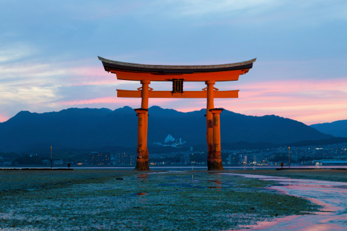 Miyajima island, Japan - June 16, 2010: View of Itsukushima Shrine at low tide on Miyajima island, Japan. The Itsukushima Torri gate is one of the most sacred and visited sites of Japan.