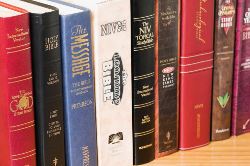 Fosston, USA - March 18, 2011:  A row of assorted Bibles including (left to right):  The Experiencing God Study Bible, New International Version (NIV);  Holy Bible, King James Version (KJV), Giant Print Center Column Reference Edition;  The Message - The Bible in Contemporary Language, Paraphrased by Eugene H. Peterson;  The Learning Bible, New International Version (NIV);  The NIV Topical Study Bible, Red Letter Edition, New International Version (NIV);  The MacArthur Study Bible, New King James Version (NKJV), Author and General Editor - John MacArthur;  Archaeological Study Bible, New International Version (NIV);  The Living Insights Study Bible, New International Version (NIV), Charles R. Swindoll - General Editor;  The One Year Chronological Bible, New International Version (NIV).
