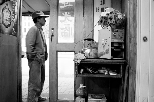 Shanghai, China - March 16, 2008: When the evening is coming , a rural migrant worker is waiting for his colleagues to have dinner together outside a small resturant located in a small street in Pudong,Shanghai.