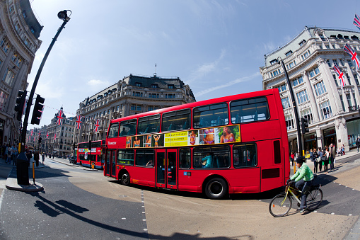 London, England, UK - May 4, 2011: a typical red bus drives in Oxford Circus in the city of London during a bright spring day. Photo taken with a fish-eye lens.