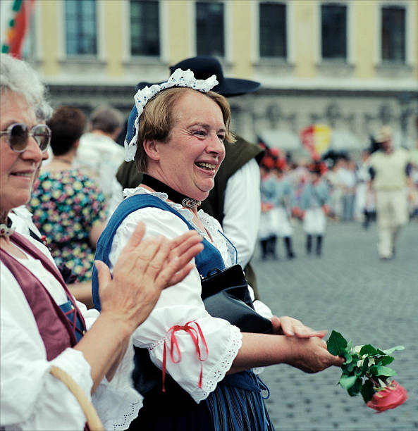 Augsburg,Germany-July,16th 1992:Two women wearingtraditional dress,one holding a rose,the other applauding,watching a parade during the Augsburg people\\'s festival.