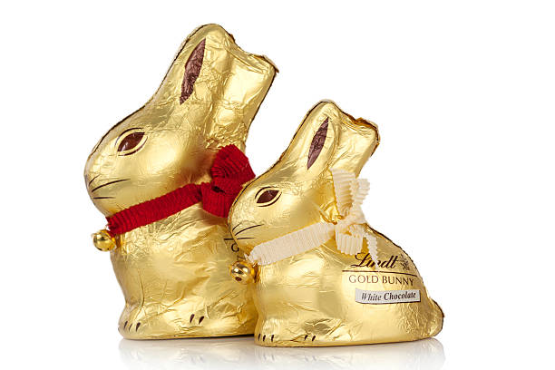 Hertfordshire, UK - April 25, 2012: Studio shot of two Lindt Gold Bunnies with their golden bells, one milk chocolate and one white chocolate, on white reflective surface