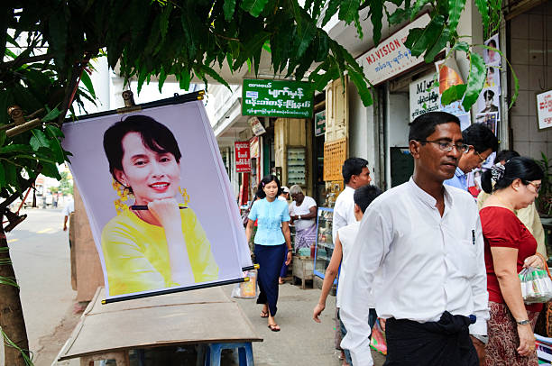 Yangon, Myanmar (Burma) - October 22, 2011: Pedestrians walk past a poster-and-stationary shop where a poster of Aung San Suu Kyi is displayed for sale. Aung San Suu Kyi, a 1991 Nobel Peace Prize laureate, is General Secretary of the National League for Democracy and has been a strong critic of the military regime.