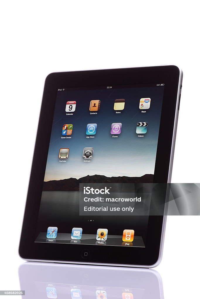 iPad Lodz, Poland - April, 9 2011: The iPad, the digital tablet with multi touch screen. iPad is owned by company Apple Inc. Side view of showing its home screen with standard icons and isolated on a white background shot on a reflective surface. Big Tech Stock Photo
