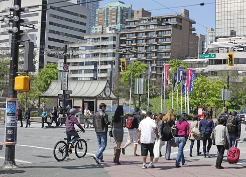 Vancouver, Canada - May 6, 2012: Pedestrians and a cyclist cross the busy intersection at Robson and Howe Street. Spring afternoon near Robson Square.
