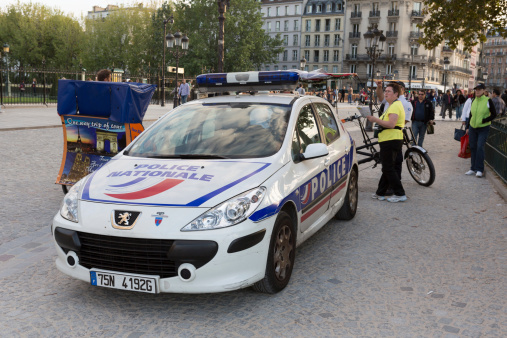 Paris, France - October 7, 2013: People at the Notre Dame Cathedral in Paris, France. Police car parked at the Notre Dame Cathedral. Many armed police have been placed around Paris' major tourist attractions because of an influx of criminal gangs from eastern Europe.