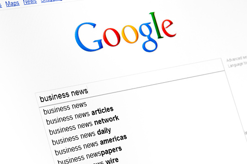 Kyiv, Ukraine - March 13, 2011: Business news text string in google search field start page. Google propose some relative search string more as pop up list. Google the most powerfull search engine in the internet.