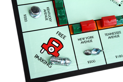 West Palm Beach, USA - July 25, 2011: This is a partial view of a Monopoly game board showing the Free Parking square with various playing pieces set  on the board.  The Race Car is resting on the Free Parking square while the Boot and Top Hat have landed on properties with multiple houses and hotels. Monopoly is a popular board game that is owned and manufactured by Hasbro.