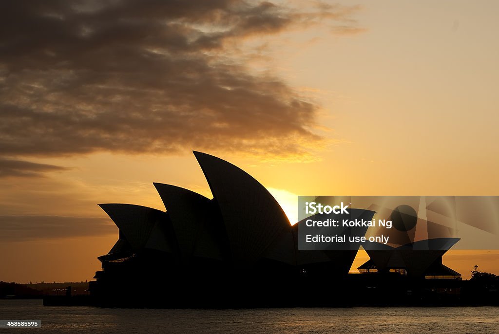 Sydney Opera House at sunrise Sydney, Australia - October 9, 2010: The Sydney Opera House, seen from The Rocks, is silhouetted against the rising sun. Architecture Stock Photo