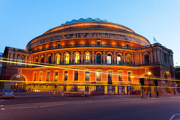 Royal Albert Hall by Night London, United Kingdom - May 2, 2011: Royal Albert Hall is lit up at dusk - light trails can be seen from a passing bus. royal albert hall stock pictures, royalty-free photos & images