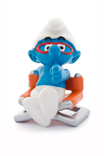 Kuala Lumpur, Malaysia - June 27th, 2010: A figurine of Brainy Smurf with red eyeglasses sitting on a director-chair. Brainy Smurf is a male character from the Smurfs, a classic series of comic about a group of small blue fictional creatures. This Smurf figure was bought from The Belgian Comic Strip Center.