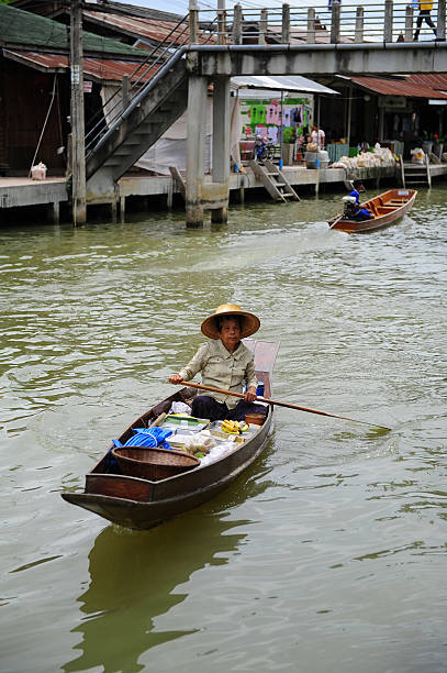 Floating market Samudsongkarm, Thailand - September 26, 2009: Trader rows a boat to sells goods at Amphawa floating market in Samudsongkarm, Thailand. mode of transport rowing rural scene retail stock pictures, royalty-free photos & images