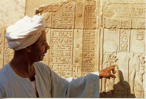 Kom Ombo, Egypt - April 17, 2000.  Temple of Haruris and  Sobek.  An Egyptian temple guide pointing to an image on the wall of the temple.