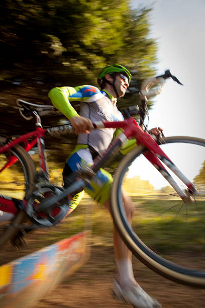 cyclocross racer llevar su bicicleta de obstáculos - cyclo cross fotografías e imágenes de stock