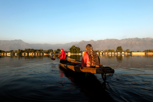 Srinagar, India - September 19, 2013: Two Muslim Indian women returning home in evening after collecting lotus leafs, which they use to feed cattle and sometime they use to sell it cattle's owner.
