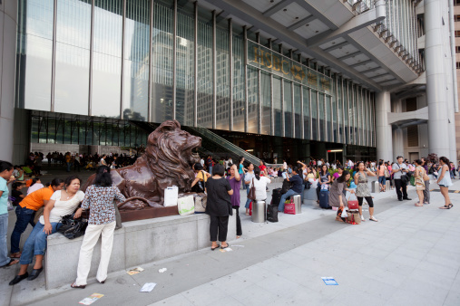 Hong Kong, China - August 7, 2011: Filipino domestic helpers gathered during Sunday at the entrance of the HSBC headquarters building in the Central District of Hong Kong. This building is located in 1 Queen\'s Road Central, Central District, Hong Kong. This building was designed by Norman Foster.