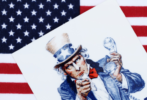West Palm Beach, USA - April 12, 2012: This is a partial view of a decal showing the iconic Uncle Sam figure with one hand pointing and the other holding a telephone.The decal is lying on an American flag background. The decal is a vintage US Customs promotional product requesting citizens to report drug smuggling. The Uncle Sam figure has been in use since at least 1917 by various US government agencies, most notably to recruit soldiers during WWI and WWII and on US postage stamps.